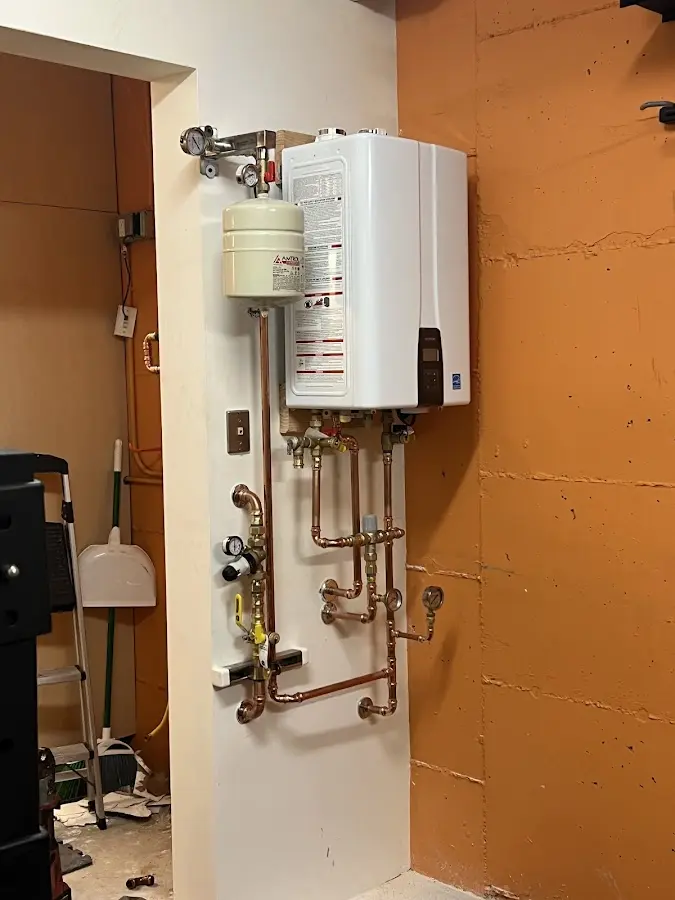 Plumbing technician inspecting water heater connections in Three Points